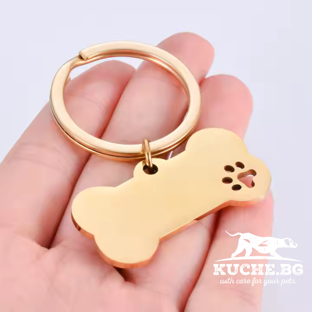 Персонализиран медальон за кучета с форма на кокал, златист цвят, на ринг в ръка.